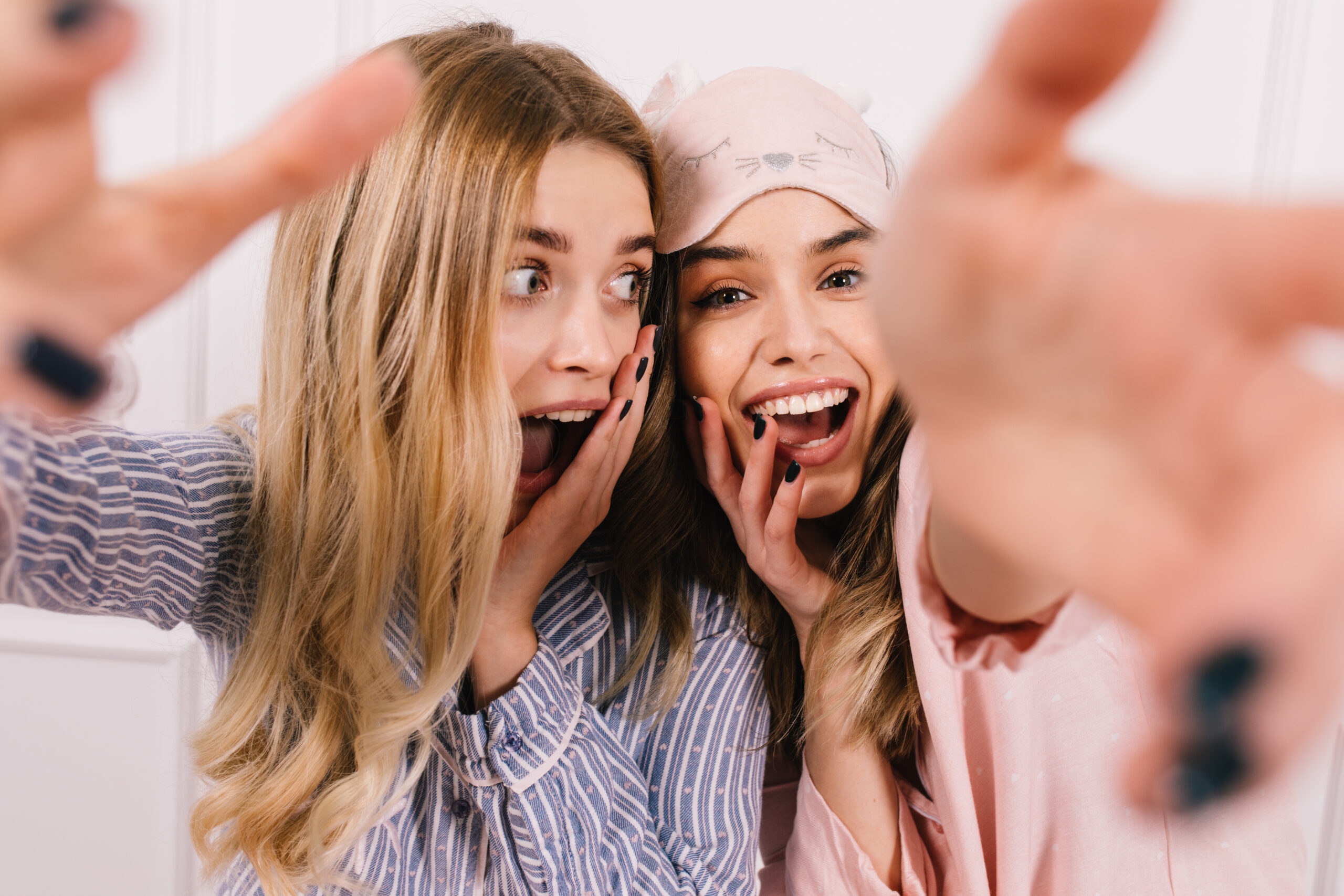 FerkoMedia - Jocund girls in pajamas fooling around together. Good-humoured friends making selfie and laughing.